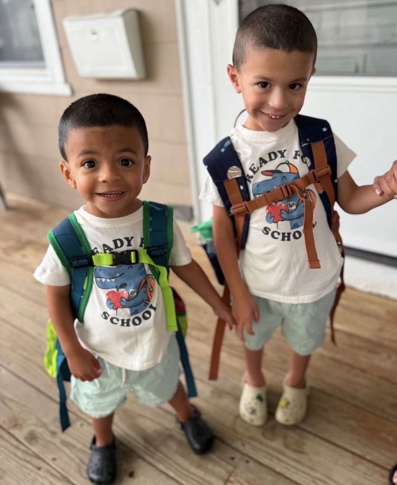 Jillian’s two young boys smiling together with their backpacks